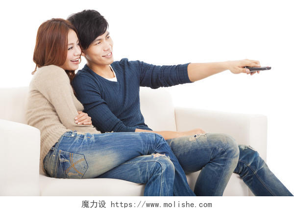 年轻的夫妇在沙发上看电视与远程控制